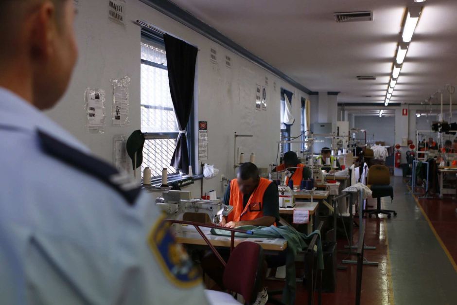A guard watches on as the inmates make garments in the textile section.