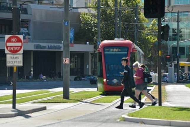 As a tram approaches, school children cross tramlines in Adelaide, South Australias, Victoria Square.
